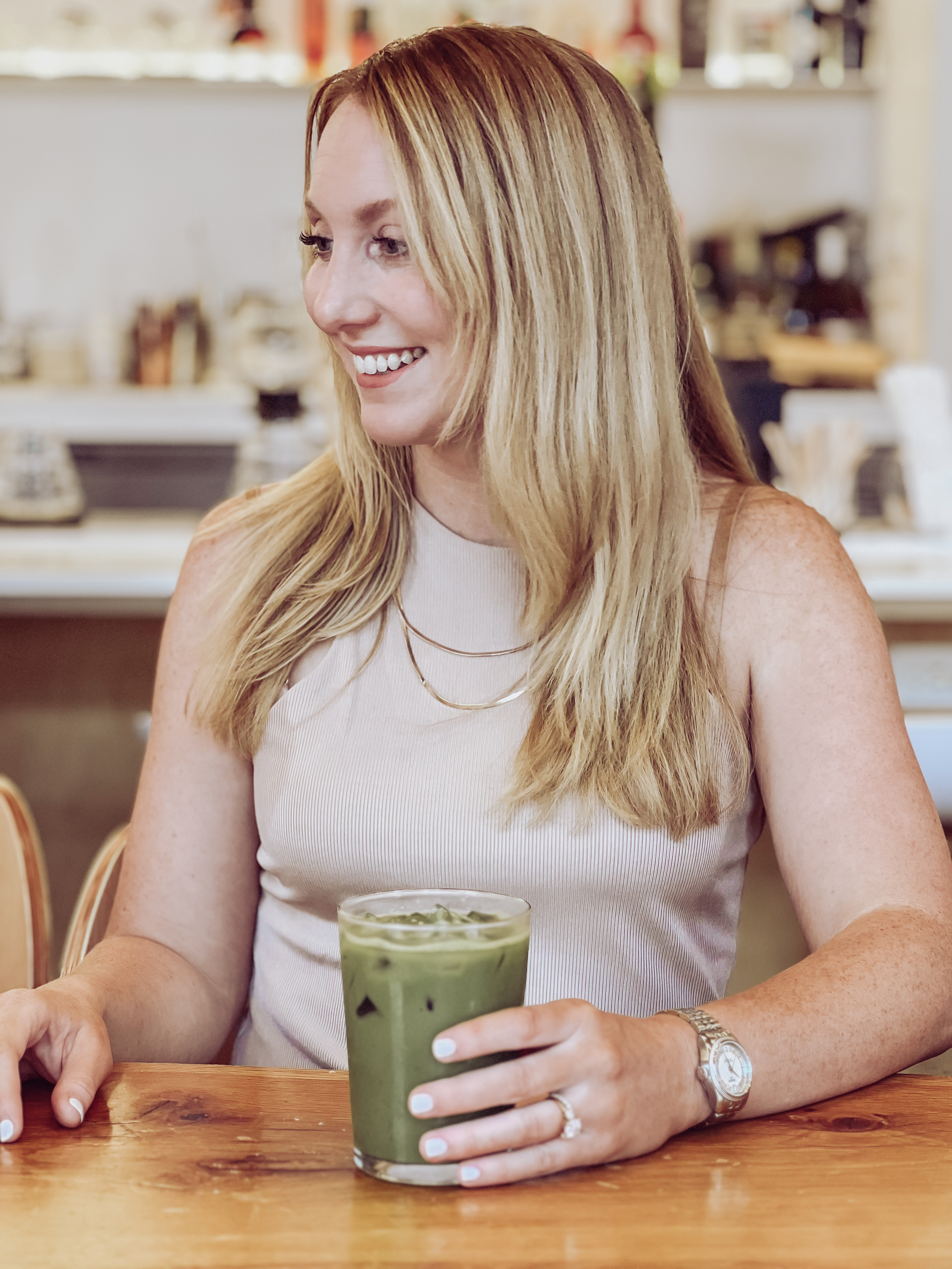 Brittany smiling at a cafe table with a green drink